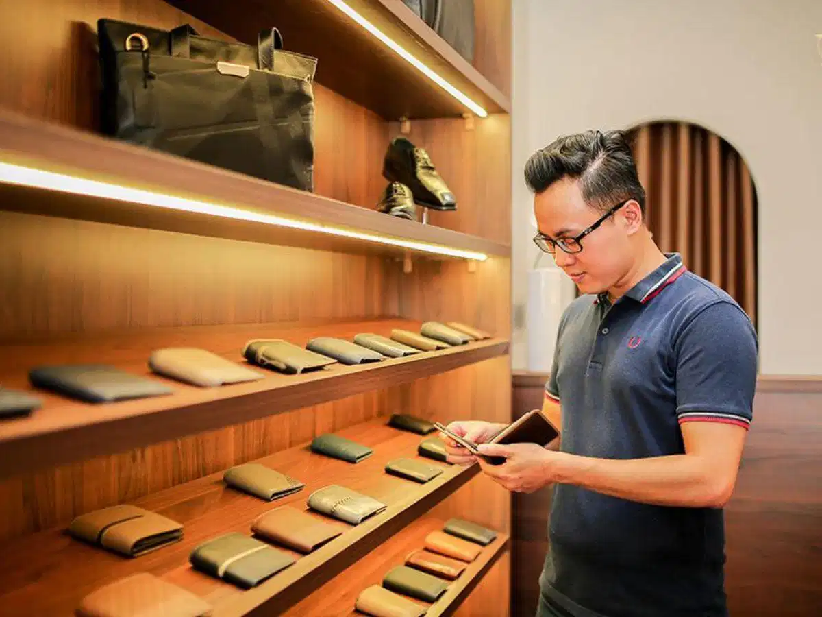 Dành thời gian kiểm tra kỹ lưỡng tại cửa hàng để chọn được chiếc ví da phù hợp Khách hàng cầm ví da kiểm tra trực tiếp phom dáng tại showroom